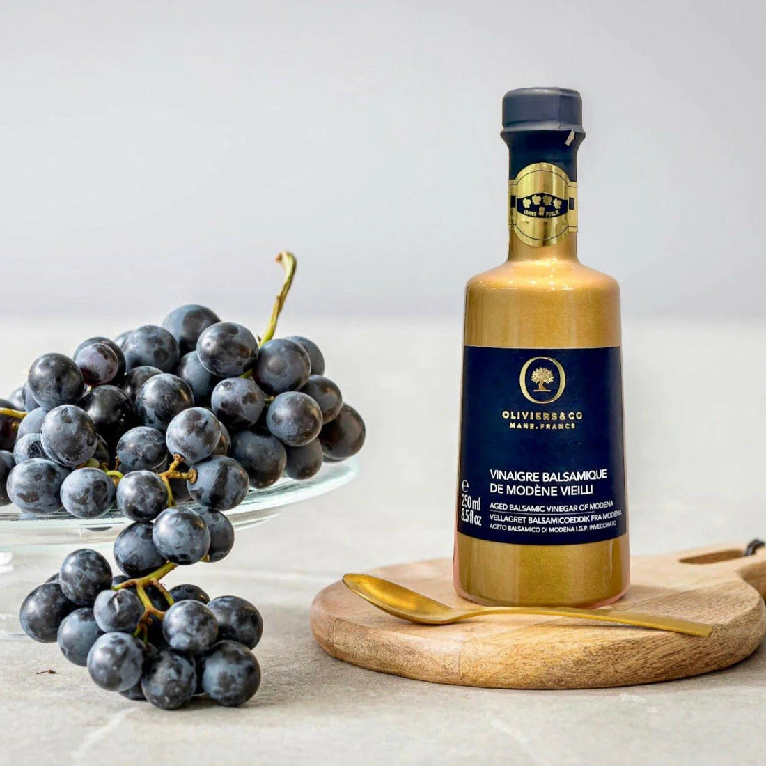 Flasche Balsamico-Essig aus Modena von Oliviers & Co mit goldener Etikette. Der Balsamico steht auf einem weißen Hintergrund und zeigt das elegante Design des Produkts, welches für seine hohe Qualität und intensiven Geschmack bekannt ist.