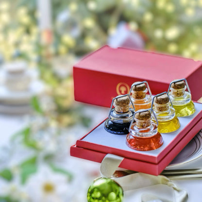 Exklusive Geschenkbox mit einer Auswahl an verschiedenen Gourmet-Ölen in eleganten Glasflaschen mit Korkverschluss. Die farbenfrohe Präsentation enthält verschiedene Sorten Olivenöl und Balsamico, perfekt für besondere Anlässe und festliche Geschenke wie Weihnachten.